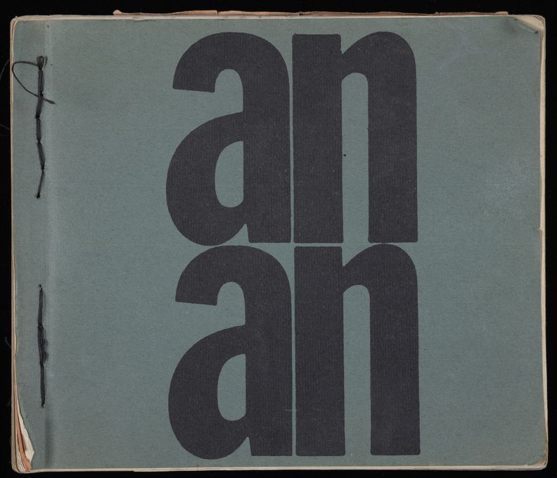 Green paper cover of square-shaped book bound at left edge with exposed black thread. The word An is printed in black twice at center, one on top of the other, covering the entirety of the middle of the page. Slight lift at corners revealing cream pages behind.