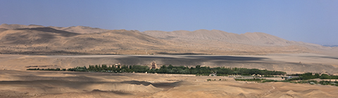 Distant view of the Mogao Caves from across the desert, showing the sand dunes in the background
