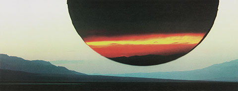 A color print depicts a stenciled sun comprised of footage from a sunset superimposed on the sky above a mountain landscape.