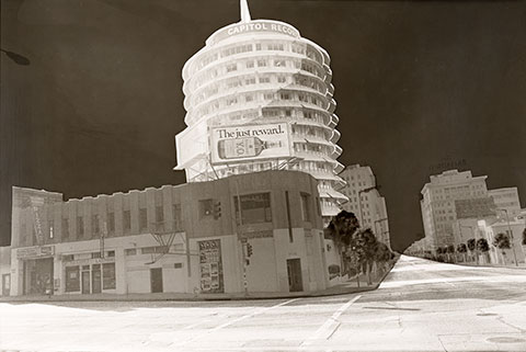 A black-and-white photograph of the Capitol Records headquarters, a multistory, circular building in Los Angeles. 